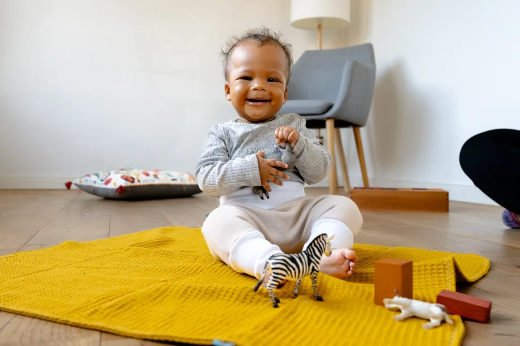 Babykleidung Neugeborene mit Spielzeug auf einem Teppich