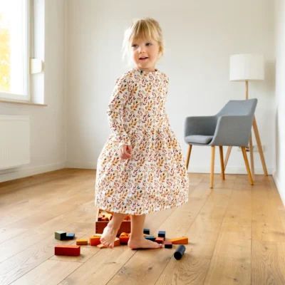 Mädchen mit langärmligem Kleid und floralem Muster